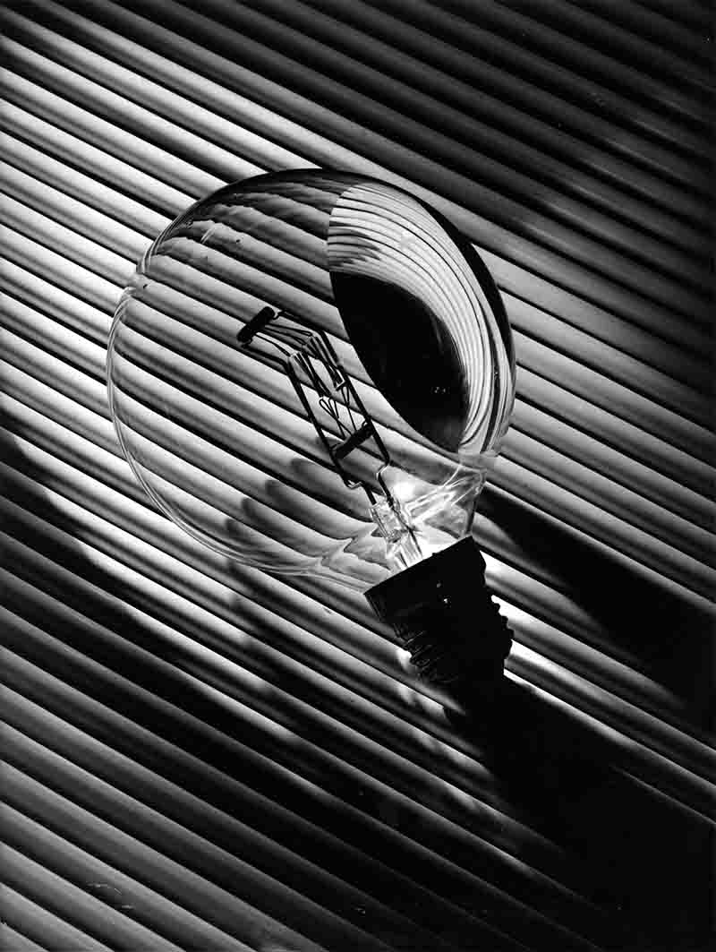 A monochrome photograph featuring a light bulb, highlighting its shape and texture in a classic black and white style.